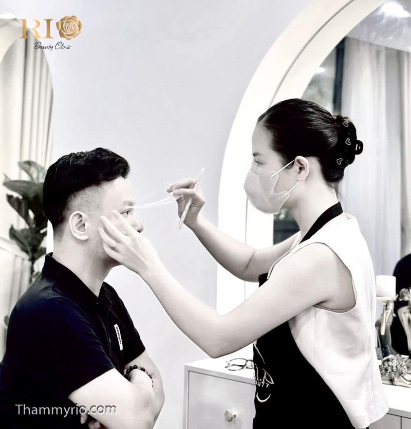 Artist Master Mely Thảo đang trực tiếp thực hiện kỹ thuật xăm chân mày nam cho khách hàng tại Rio Beauty Clinic, sử dụng công nghệ đi sợi siêu thực đỉnh cao.