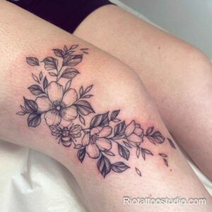 Delicate floral and bee knee surgery scar tattoos in Hanoi.