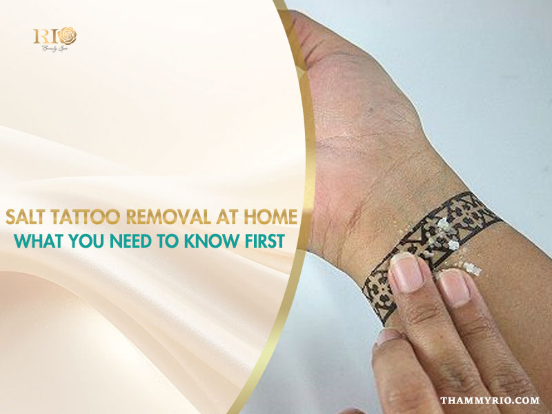 A person applying salt to a black ink wrist tattoo for salt tattoo removal at home.