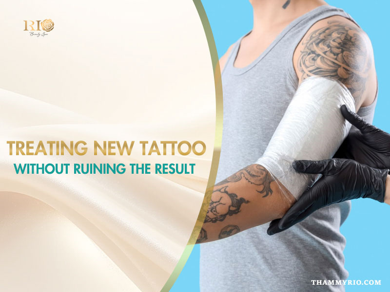 Professional artist applying plastic wrap for treating new tattoo on a man's arm.