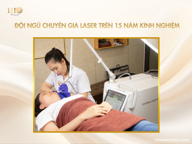 Chuyên gia mặc blouse trắng đeo găng tay cẩn thận chiếu tia laser điều trị da cho khách hàng