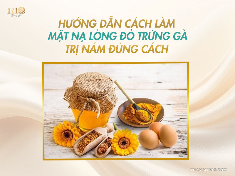 Bát tinh bột nghệ vàng tươi, hũ mật ong và hai quả trứng gà nguyên vẹn trên nền gỗ trắng sáng